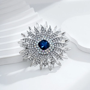 Broche tournesol élégante avec cristal bleu et strass blancs sur monture argentée