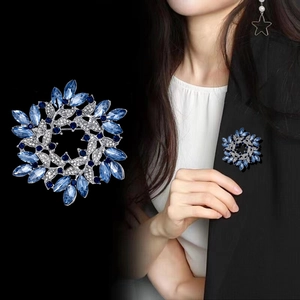 Elegante spilla a corona con cristalli blu e modella che indossa su giacca nera
