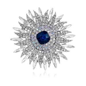 Broche tournesol avec pierre bleue et cristaux blancs sur fond blanc avec reflet