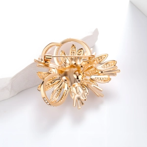 Elegante spilla a fiore dorata con perle e strass che mostra la struttura della spilla