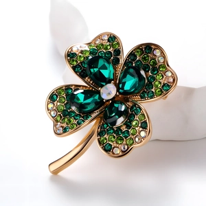 Elegant gold four-leaf clover brooch featuring green pear-shaped gemstones and crystals
