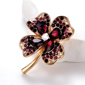 Elegant four-leaf clover brooch with red gems and purple crystals on gold finish