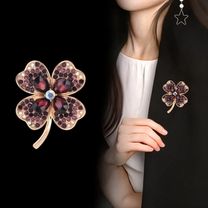 Luxurious four-leaf clover brooch with purple crystals and stem on a golden base