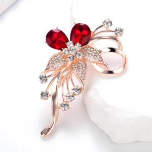 Elegante broche de flor en oro rosa con cristales rojos sobre base de piedra blanca