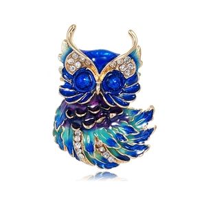 Detailed macro view of an enamel owl brooch featuring blue crystal eyes and colorful rhinestones