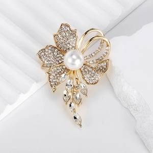Luxurious gold flower brooch with pearls, tassels, and crystals on a minimalist stone base