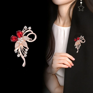 Broche floral de oro rosa con cristales rojos y pedrería mostrado en una chaqueta