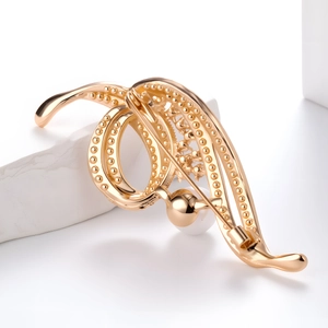 Elegant gold musical note brooch with pearls and crystals on a white marble pedestal