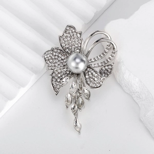 Elegant flower brooch with white crystals, grey pearl, and crystal tassel on stone base