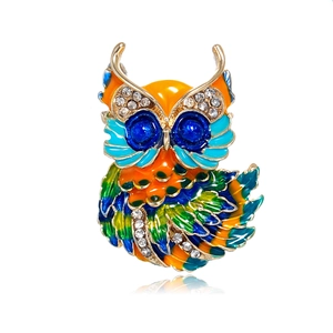Detail of owl brooch with colorful enamel feathers and blue crystal eyes on gold base