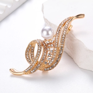 Elegant gold musical note brooch with white pearl and sparkling crystals on white marble