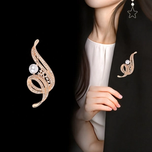 Elegant gold brooch with sparkling crystals and a pearl shown on a black suit lapel