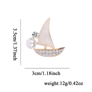 Golden sailboat brooch with rhinestone inlay and white pearl detail on white background