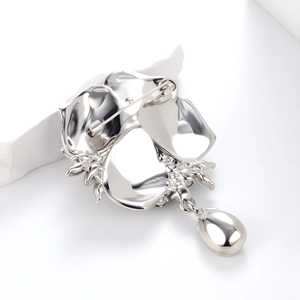 Elegant silver rose brooch with long pin buckle and oval metallic pendant on white background
