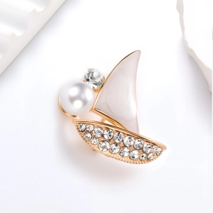 Exquisite sailboat brooch with white pearls and rhinestones on a minimalist background