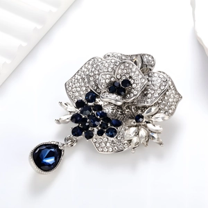 Elegant silver rose brooch with white crystals and large dark blue teardrop pendant