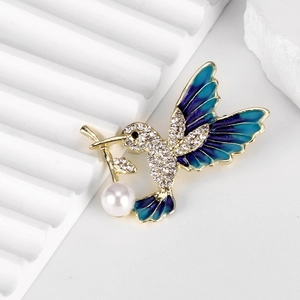 Elegant hummingbird brooch with blue enamel wings, crystals and pearl drop detail