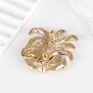 Spilla classica maschera veneziana con piuma smaltata in finitura oro su sfondo bianco
