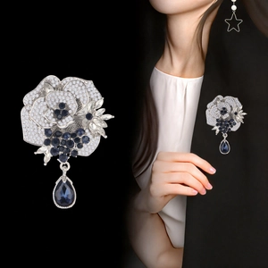 Elegant silver rose brooch with white crystals and dark blue pear-shaped drop pendant