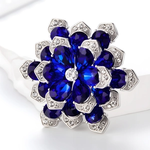 Macro shot of silver cornflower brooch with deep blue teardrop gems and zircon details