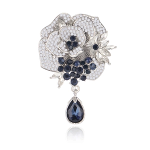 Elegant silver rose brooch with blue crystals and a teardrop pendant on white background