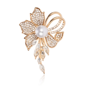 Macro detail of gold-plated flower brooch with pavé rhinestones and a white pearl drop