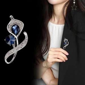 Elegante Blumenbrosche mit blauen Kristallen und Steinen an einem schwarzen Blazer
