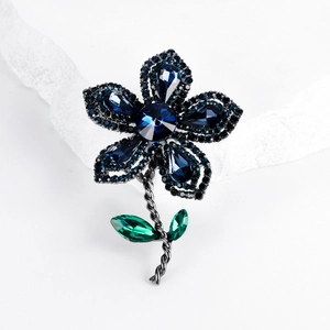 Broche fleur vintage élégante avec cristaux bleu foncé et feuille verte sur pierre