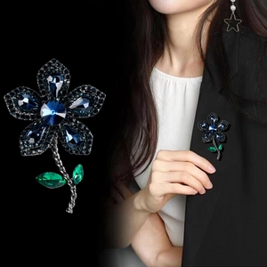 Broche fleur vintage élégante avec cristaux bleus et verts sur un blazer noir classique