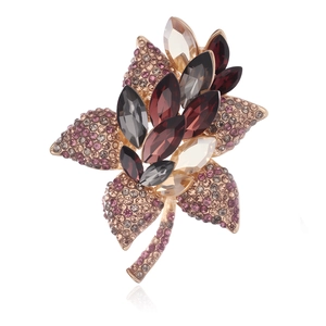 Détail d'une broche florale en métal doré rose sertie de cristaux multicolores