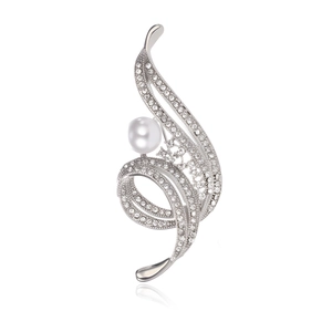 Macro shot of silver spiral brooch with sparkling rhinestones and a white pearl