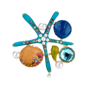 Detailed macro view of starfish and seashell brooch with colorful enamel and crystals