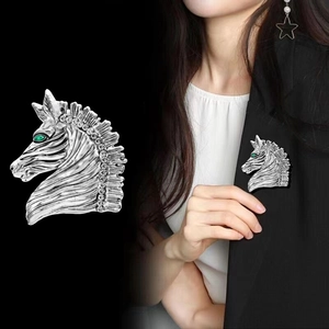 Retro zebra head brooch with green gemstone eye and rhinestones on black background