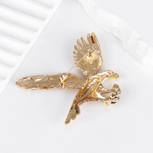 Golden eagle brooch with back safety pin clasp on an elegant minimalist white background