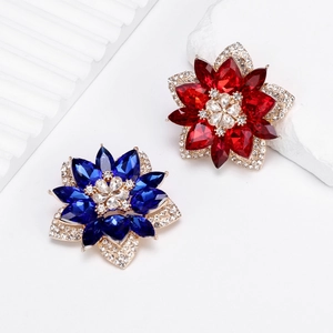Detailed macro view of faceted red and blue crystal flower brooches with gold plating