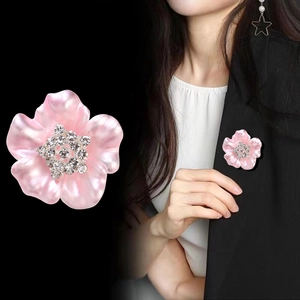 Broche fleur rose avec strass brillants sur le revers d'un tailleur noir pour femme