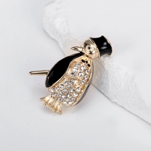 Elegant penguin brooch with black enamel and sparkling rhinestones on a stone pedestal