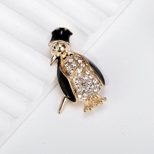 Elegant penguin brooch featuring black enamel hat and sparkling pave crystals on gold base