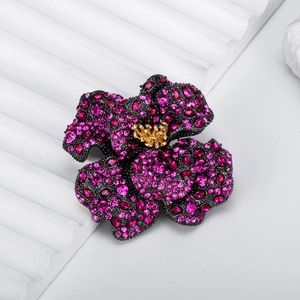 Luxury vintage rose brooch with pink crystals and gold stamens on a black alloy base
