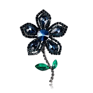 Détail d'une broche fleur vintage avec cristaux bleu foncé et tige florale plaquée noire