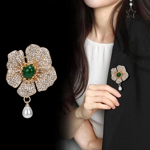 Broche camélia étincelante avec pierre verte, cristaux blancs et perle pendante