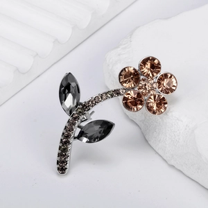 Elegant flower brooch with champagne crystals and grey leaves on a minimalist white base