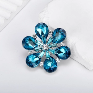 Élégante broche fleur avec cristaux bleus en goutte et base argentée sur une pierre