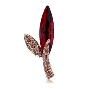 Macro shot of elegant rose gold leaf brooch with large red crystal and micro-paved diamonds