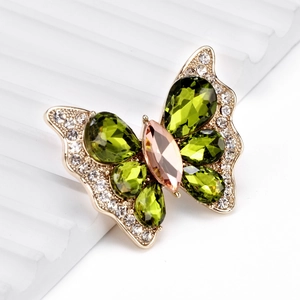 Broche papillon élégante en cristal vert olive et strass sur un socle blanc ondulé