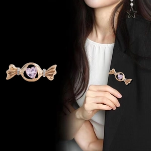 Broche bonbon japonaise en or rose avec cristal rose épinglée sur un blazer noir