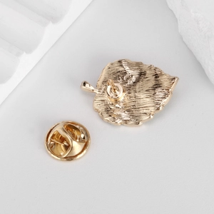 Detailed back view of a golden leaf brooch with butterfly clutch and brushed texture