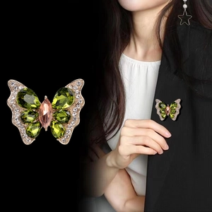 Élégante broche papillon avec cristaux roses et verts sur un blazer noir