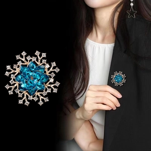 Luxuriöse blaue Kristall-Blumenbrosche mit Goldplattierung auf einem schwarzen Sakko