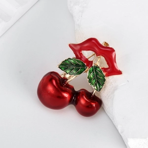 Creative red lips and cherry brooch with green enamel leaves on a stone background